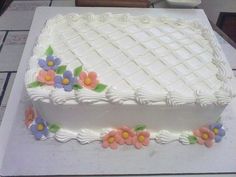 a cake with white frosting and flowers on it sitting on top of a table