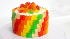 a multicolored cake with white frosting and gummy bears on the top