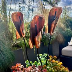 three glass flowers in a pot with succulents