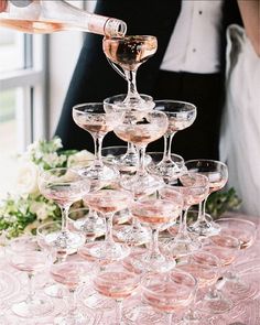 a bride and groom are pouring champagne into wine glasses for the guests to take home