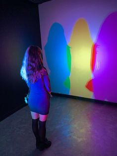 a woman standing in front of a colorful wall