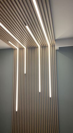 the light is shining down on the ceiling in this modern style room with vertical striped wood slats