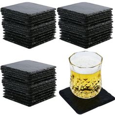 a glass of beer sitting next to a stack of black coasters on top of each other