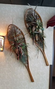 two wooden canoes decorated with pine cones and greenery are hanging on the wall