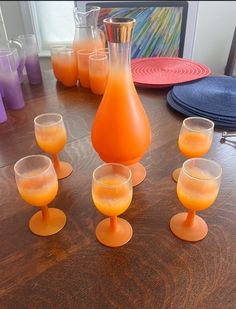 there are many glasses on the table with orange liquid in them and one is empty