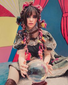 a woman sitting on the ground holding a crystal ball