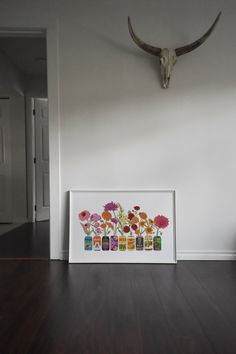 an animal's head hangs on the wall next to a framed photo with flowers