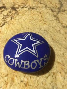 a blue cowboy's button sitting on top of a marble counter with the word cowboys painted on it