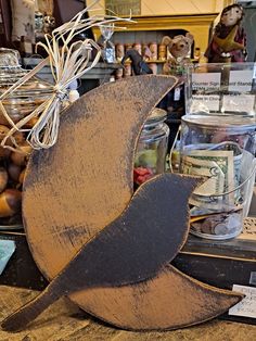 a wooden bird sitting on top of a table next to jars and other items in a store