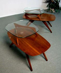 three tables with glass tops and wooden legs on carpeted flooring in an empty room