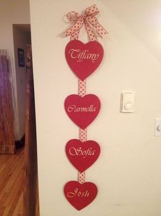 three hearts hanging from the wall with names on them