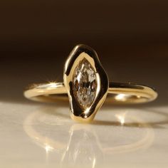 a yellow gold ring with a pear shaped diamond on it's center and sides