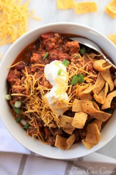 a white bowl filled with chili and tortilla chips on top of a table