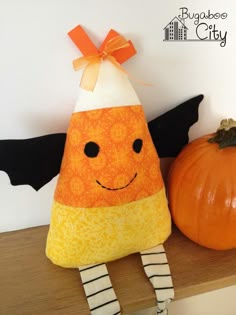 an orange and white pumpkin sitting on top of a shelf next to a black bat