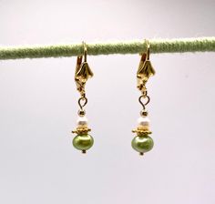 Tiny dainty green and white pearl earrings with a touch of vermeil gold dangle from gold plated leverback shell earwire. Perfect for a spring wedding or any garden party. The earrings are about 5/8 inch long, measured from the end of the earwire. Comes nestled comfortably on a bed of cotton in a white jewelry box. NA-822-0624-1111 Traditional Green Dangle Pearl Earrings, Fine Jewelry Green Pearl Earrings For Gift, Green Dangle Pearl Earrings With Ear Wire, Elegant Green Pearl Charm Earrings, Green Pearl Charm Drop Earrings, Hypoallergenic 14k Gold-filled Dangle Pearl Earrings, White Pearl Earrings, Carmel Ca, Green 14k Gold-filled Dangle Earrings