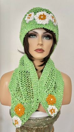 a mannequin wearing a green knitted hat and scarf with flowers on it