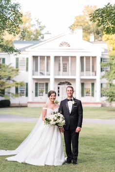 a bride and groom standing in front of a large white house