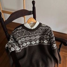 a sweater hanging on a wooden chair in a room