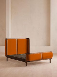 an orange couch sitting on top of a hard wood floor next to a white wall