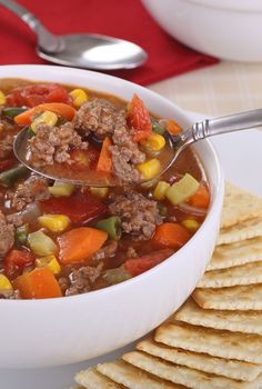 a white bowl filled with soup next to crackers