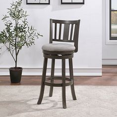 a bar stool next to a potted plant in front of a wall with pictures on it