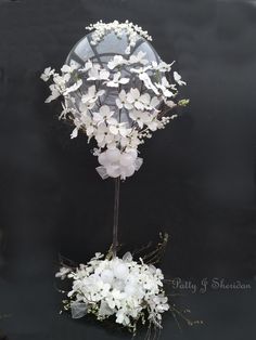 a bouquet of white flowers sitting on top of a black table next to a mirror