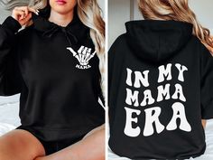 "This cozy hoodie is the perfect gift for a mama ( or for yourself of course)!  Featuring the saying \"In my mama era\" in bold letters on the back, and a \"mama\" with skeleton hand on the front, this shirt is stylish and cute all year wear. For the premium Comfort Colors® Hoodie: https://www.etsy.com/listing/1528220617/trendy-in-my-mom-era-hoodie-comfort?click_key=f3b83198336362f5e71409c4e19720de3163d03a%3A1528220617&click_sum=977e8021&ref=shop_home_active_21&pro=1&sts=1 𝐇𝐎𝐖 𝐓𝐎 𝐎𝐑𝐃𝐄𝐑 1. Select the size & color when applicable 2. Add the personalization (name, design etc) when required 3. Add to Cart & submit your order. 4. If ordered over $35, we have FREE shipping for you! 𝐀𝐋𝐖𝐀𝐘𝐒 𝐇𝐀𝐍𝐃𝐌𝐀𝐃𝐄 * Each item is handmade and made to order here in Florida! * We carry sever Cotton Hooded Hoodie For Mother's Day, Mother's Day Hooded Hoodie With Letter Print, Drip Hoodie, Motivational Hoodies, Bold Letters, Y2k Hoodie, Moms Club, Skeleton Hand, Cozy Hoodie