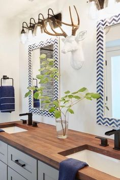 a bathroom with two sinks and a deer head mounted to the wall above it's mirror