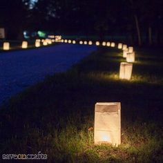 some paper bags are lit up in the grass at night with lights on each side