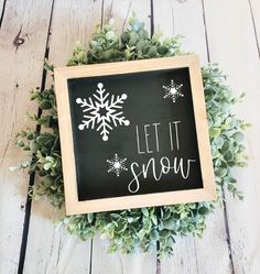 a chalkboard sign that says let it snow on top of a wreath with succulents