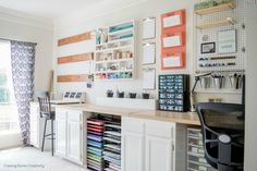 a home office with lots of crafting supplies on the desk and shelves above it