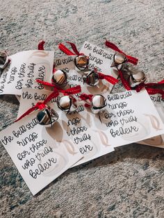 some bells are laying on the ground with red ribbon around them and tags attached to them