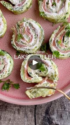 a pink plate topped with cucumber rolls covered in cream cheese and lettuce