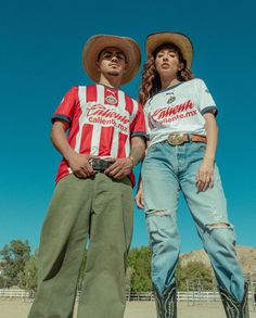 two people standing next to each other wearing cowboy hats and shirts with the same color on them