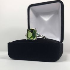 Beautiful Emerald Cut Peridot & White Sapphire Ring * Emerald Cut Peridot* Measures 10x8mm * Brilliant Cut White Sapphire Accents measure 3mm Round each * Solid Sterling Silver (Also available in 14k Gold -message me for current pricing & handling time details) * Sized to order - Select your Size Hallmarked & Gift Ready! Matching Earrings and Pendant Necklace also available! *This Peridot is Laboratory Grown Simulate . It is identical to the genuine stone in every way, including chem Emerald Cut Green Topaz Ring With Diamond, Green Emerald Cut Topaz Ring With Diamond, Green Topaz And Diamond Anniversary Ring, Green Topaz Diamond Ring For Anniversary, Green Three Stone Emerald Cut Jewelry, Green Emerald Cut Topaz Ring With Prong Setting, Green Three Stone Fine Jewelry, Anniversary Green Topaz Ring In Prong Setting, Fine Jewelry Green Topaz Ring Emerald Cut