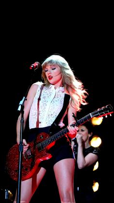 taylor swift performing with her guitar at the concert