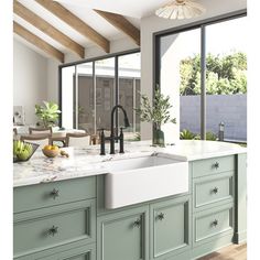 a kitchen with green cabinets and white counter tops, an open window to the backyard