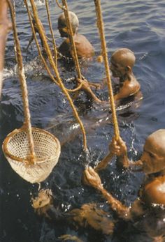 several people in the water with ropes attached to their heads and hands holding onto something that is floating on top of them