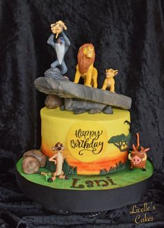 the lion king cake is decorated with figurines on it's top tier