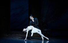 a man and woman dance on stage in the dark with their arms around each other