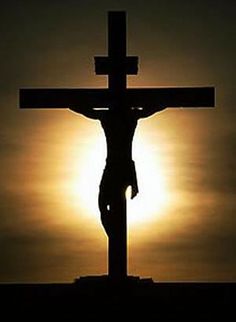 the crucifix is silhouetted against a sunset