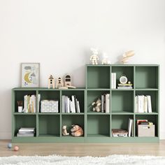 a green shelf with books and toys on it in the corner of a white room