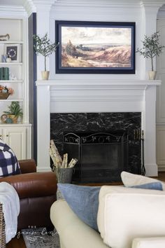 a living room filled with furniture and a painting on the wall above the fire place