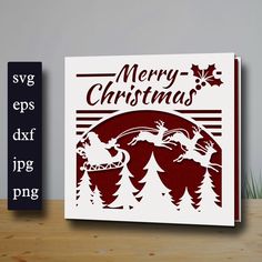 a christmas card with santa and reindeers in the woods on top of a wooden table