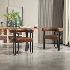 two brown leather chairs sitting next to each other on top of a tile floor in front of a wooden table