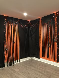 an empty room with black curtains and orange lights on the wall, decorated with chains