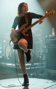 a woman in black dress playing guitar on stage