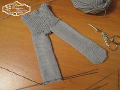 a pair of gray knitted leg warmers sitting on top of a wooden table