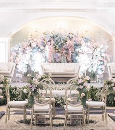 a table with chairs and flowers in front of a floral display on the wall behind it