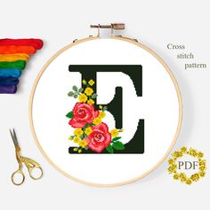 a cross stitch pattern with flowers and the letter d on it, next to scissors